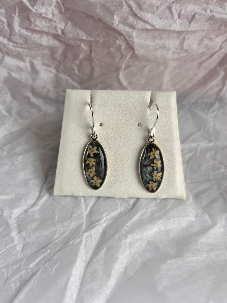 Pair of earrings on a white card with a textured gray background