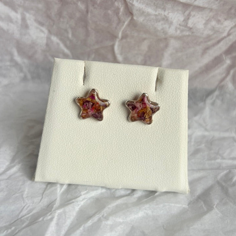 Star-shaped earrings on a white card with a textured gray background