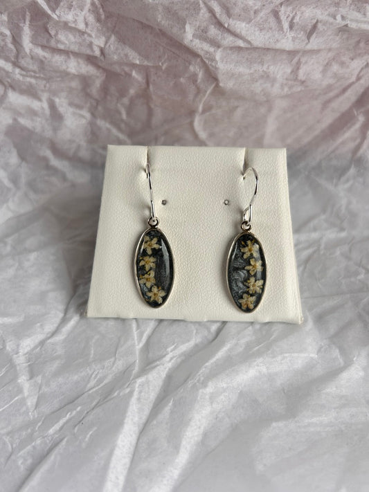 Pair of earrings on a white card with a textured gray background