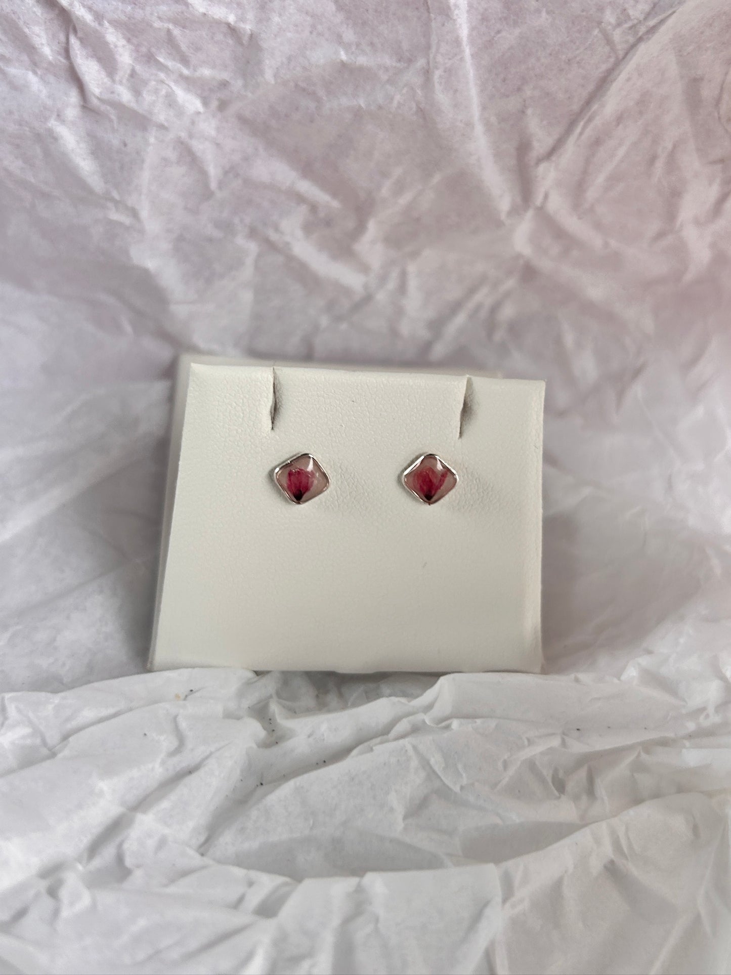 Pair of earrings in a white box on a textured white surface
