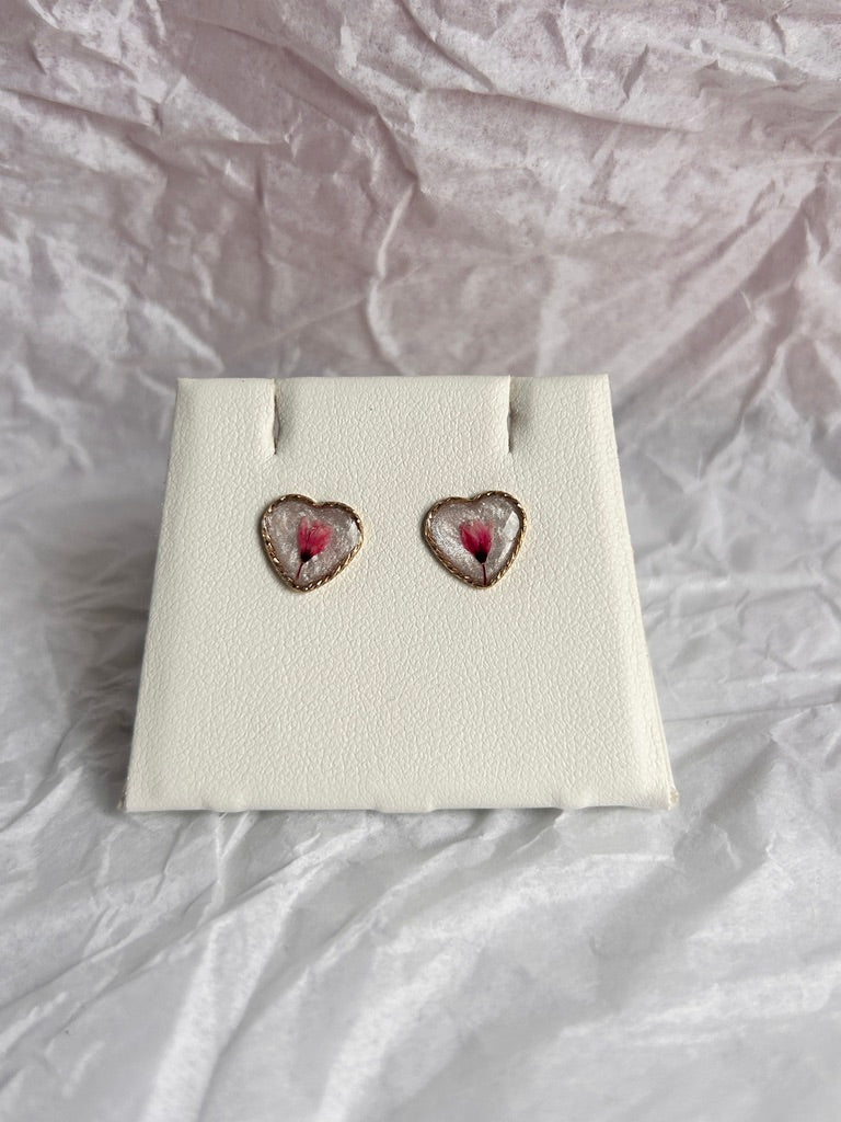 Heart-shaped earrings on a white card with a textured light gray background