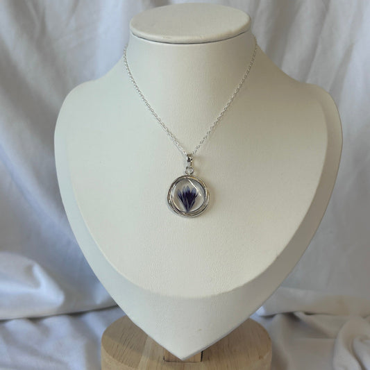 Silver necklace with a pendant on a white mannequin bust against a white background
